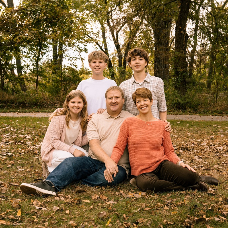 McCarthy family portrait outside on the grass surrounded by autumn leaves